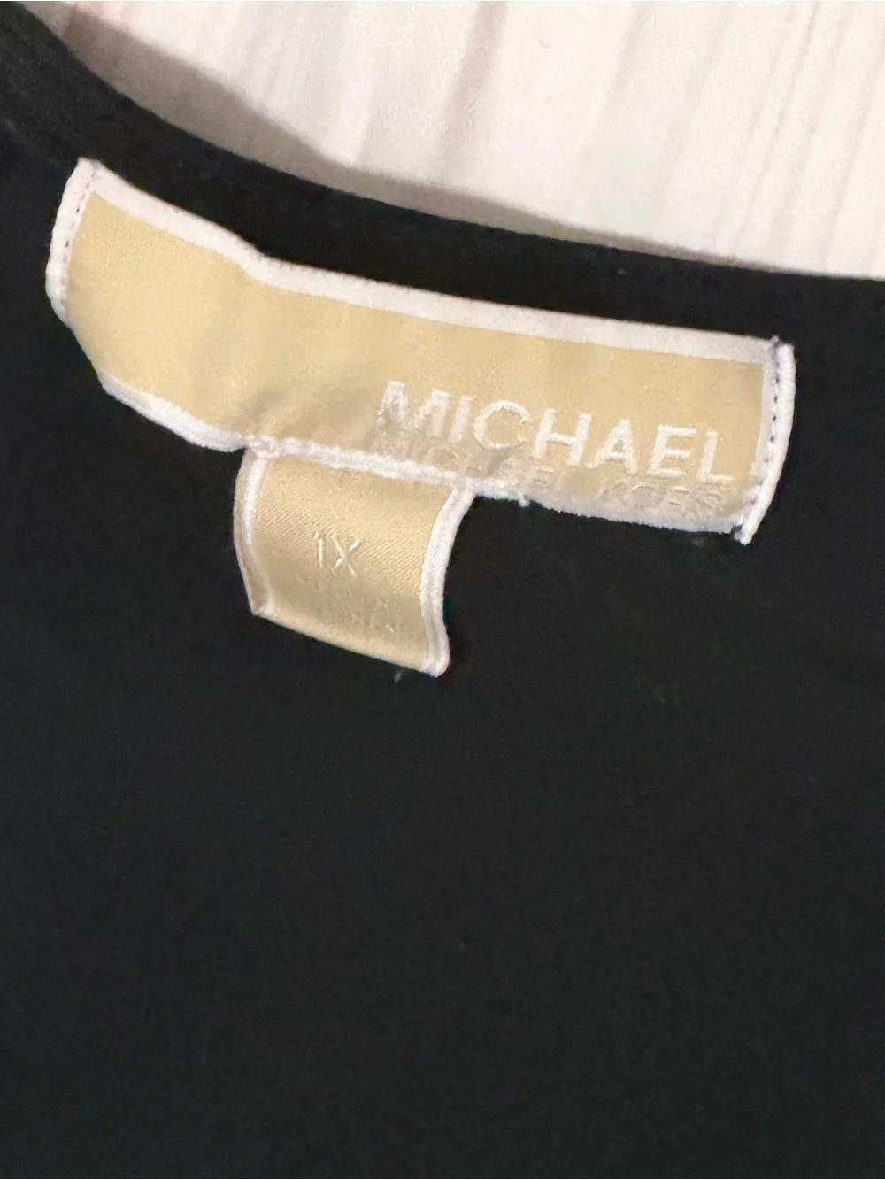 Black Michael Kors blouse with a V-neck, faux-wrap design, and gold bar at the w